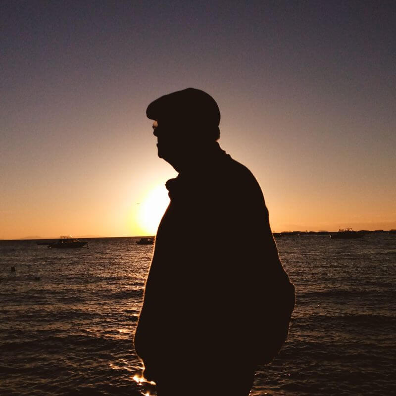 Image d'un homme qui porte une casquette plate devant un coucher de soleil